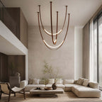 Hung in a double-height living room with a cream corner sofa, this Clérachic pendant shows its brown straps and two lit LED curves.