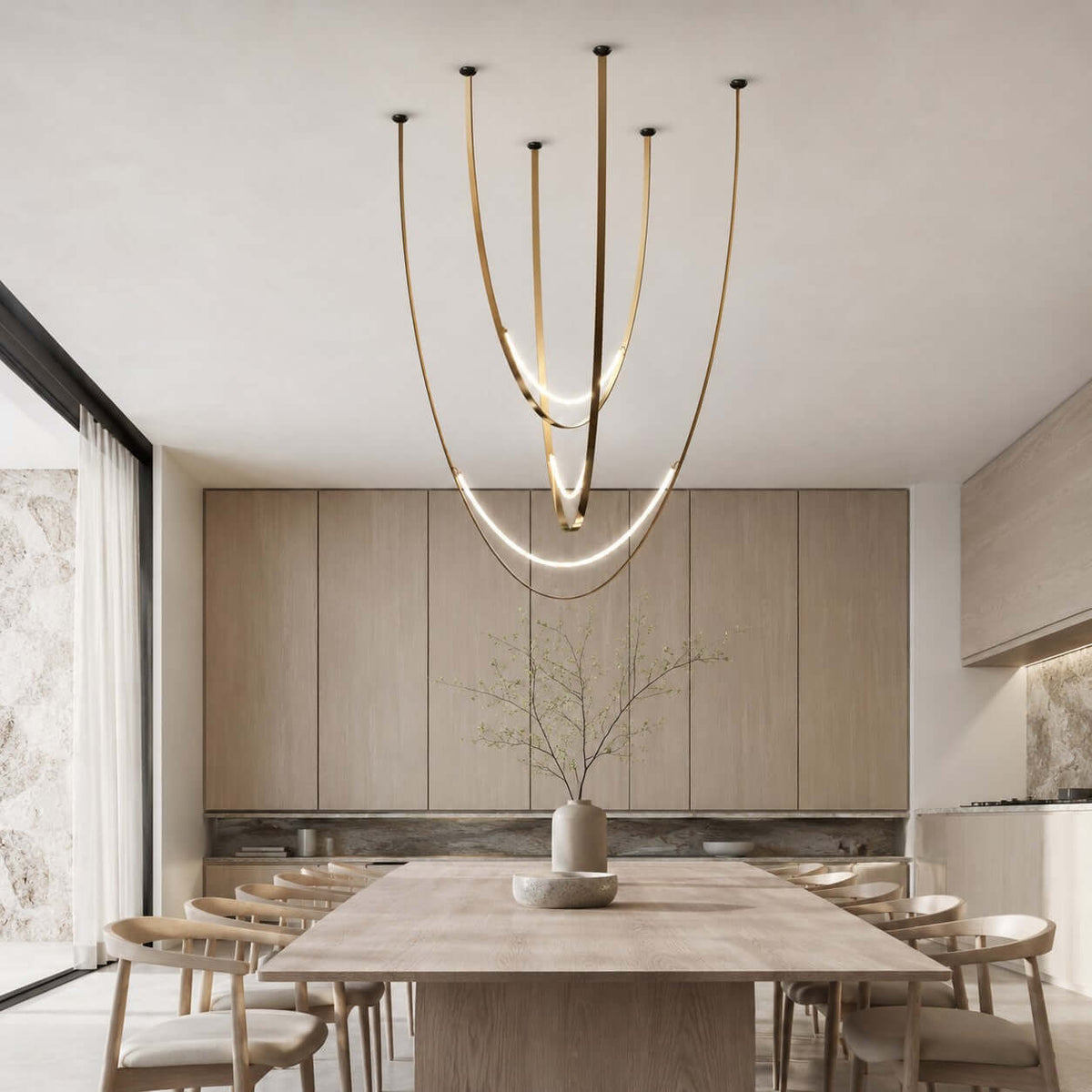 Over a long pale wood table in front of tall veneer cabinets, this Clérachic pendant hangs on brass-toned straps with lit arcs.