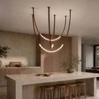 Over a stone kitchen island with wooden stools, this Clérachic pendant hangs in brown straps, its lower LED arc glowing in front of a timber panel.