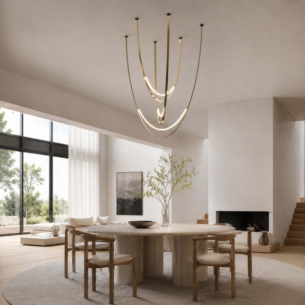 In an open room with a glazed wall and a fireplace, this Clérachic pendant on brass-toned straps hangs above a round table and wooden chairs.