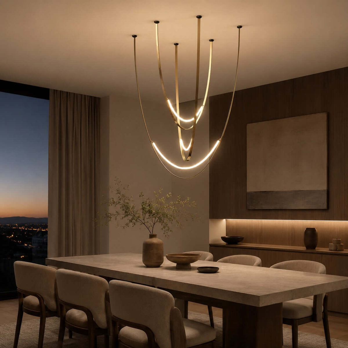 On a city evening, this Clérachic pendant hangs on slim brass-toned straps over a stone dining table with a wall-length window behind.