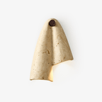 Draped travertine wall sconce from Clérachic on a plain light backdrop, with a round walnut-tone knob at the top and a soft glow below the fold.
