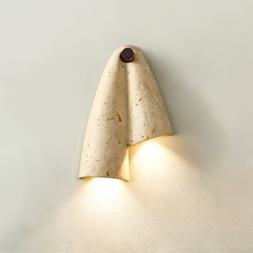 Mirror-image Clérachic wall sconce, lit, with its fold opening to the left and warm light washing the wall below.