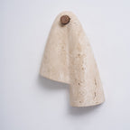 Side-angled view of the unlit Clérachic wall light, the draped stone casting a soft shadow on a pale wall.