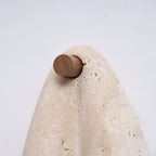 Close view of the round walnut-tone knob and the curved top of the travertine on this Clérachic wall light.