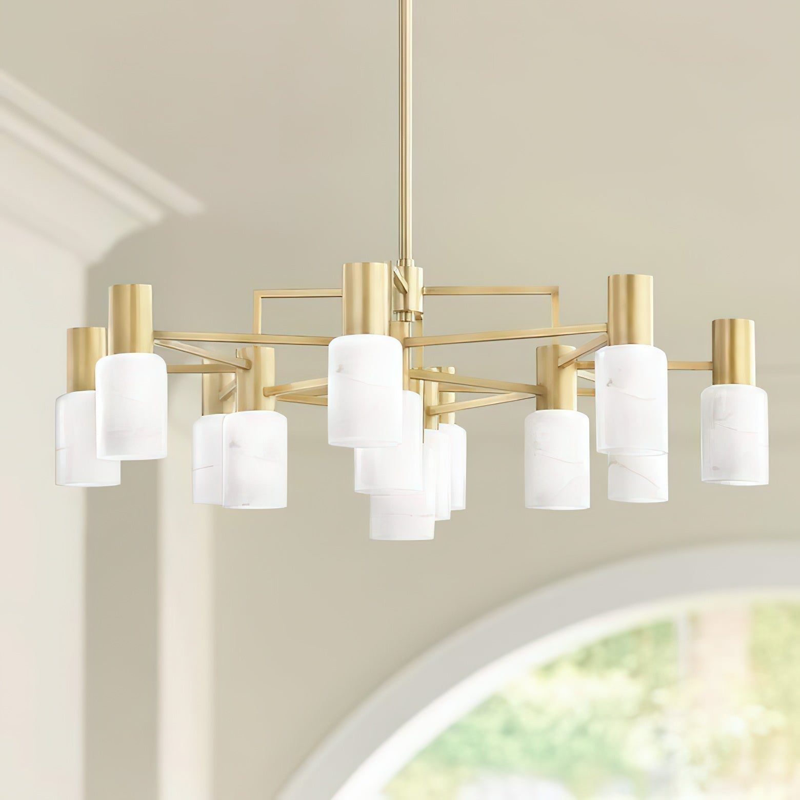 The Clérachic brass chandelier hung in a room with a coved ceiling, alabaster shades lit above an arched window.