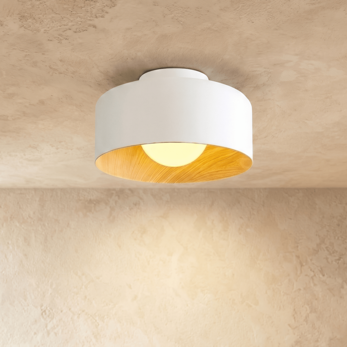 Clérachic white metal drum ceiling light with a wood-grain interior and an opal ball glowing warm, on a limewashed ceiling.