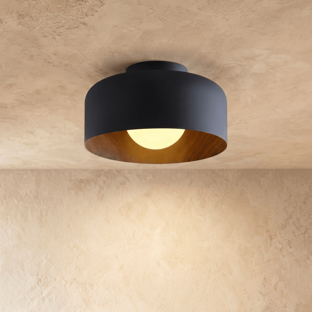 Clérachic matt black drum ceiling light with a wood-grain interior and a softly lit opal ball, on a limewashed ceiling.