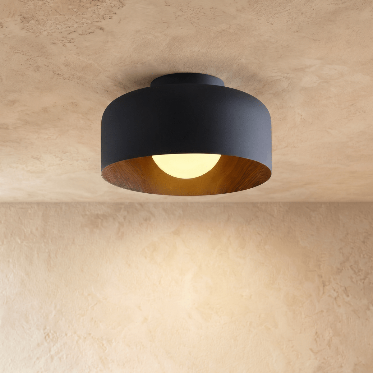 Clérachic matt black drum ceiling light with a wood-grain interior and a softly lit opal ball, on a limewashed ceiling.