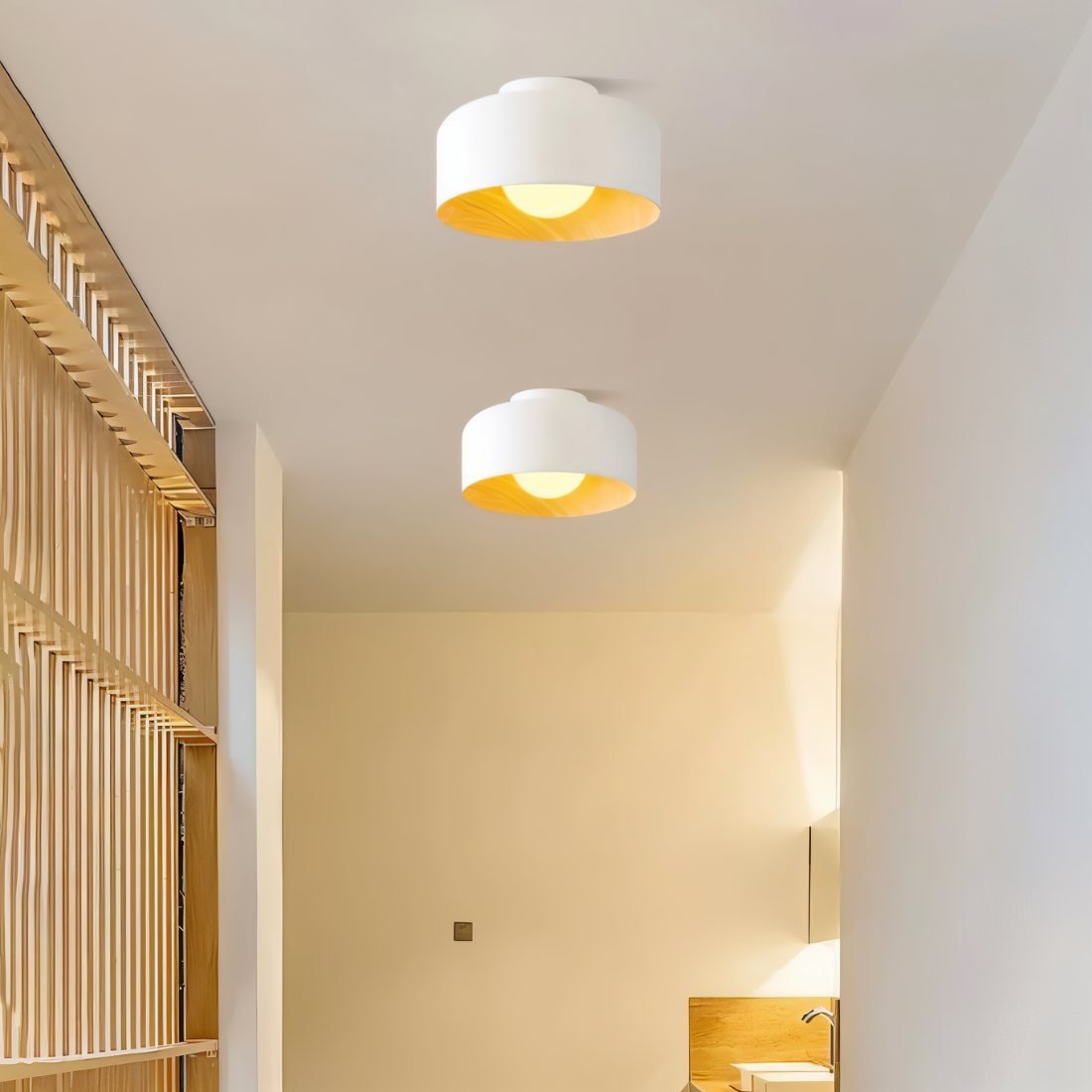 Clérachic two white wood-lined drum ceiling lights in a pale hallway beside a slatted timber screen.