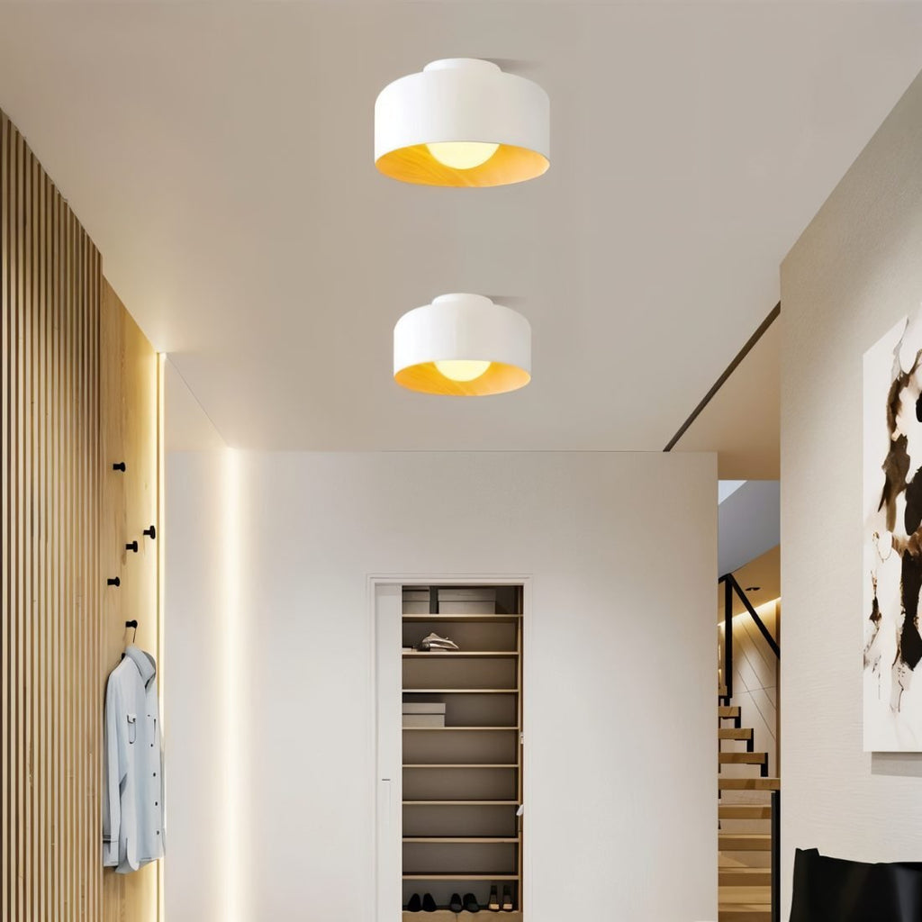 Clérachic two white drum ceiling lights glowing warm in a hallway with slatted wood panelling, a shoe cupboard and stairs.