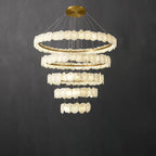 The Clérachic Ecliptica alabaster chandelier lit against a dark grey wall, tiers tapering downward.