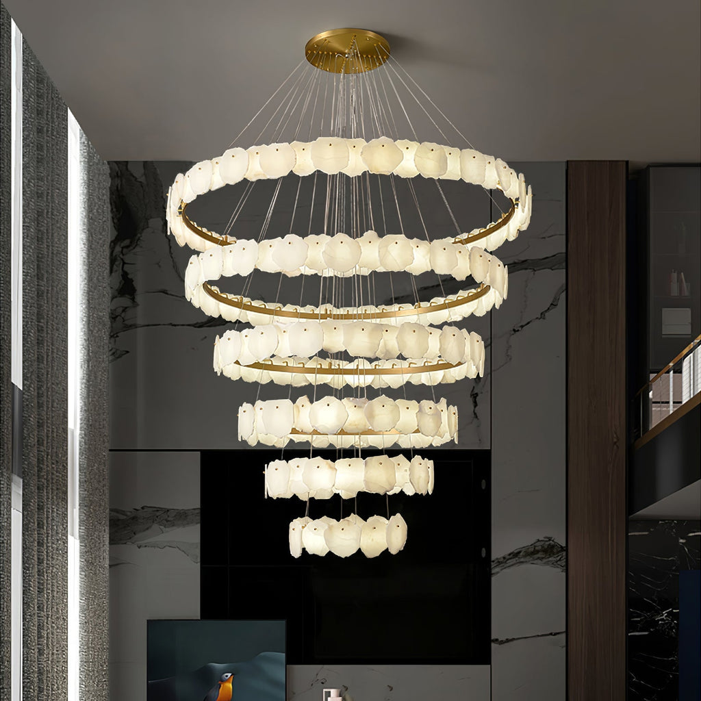 The Clérachic Ecliptica chandelier dropping through a marble stairwell in a modern entrance hall.