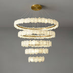 Clérachic Ecliptica chandelier seen from below against a pale ceiling, brass rings glowing warm.