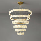 The Clérachic Ecliptica chandelier lit on grey, warm light washing across the layered petals.