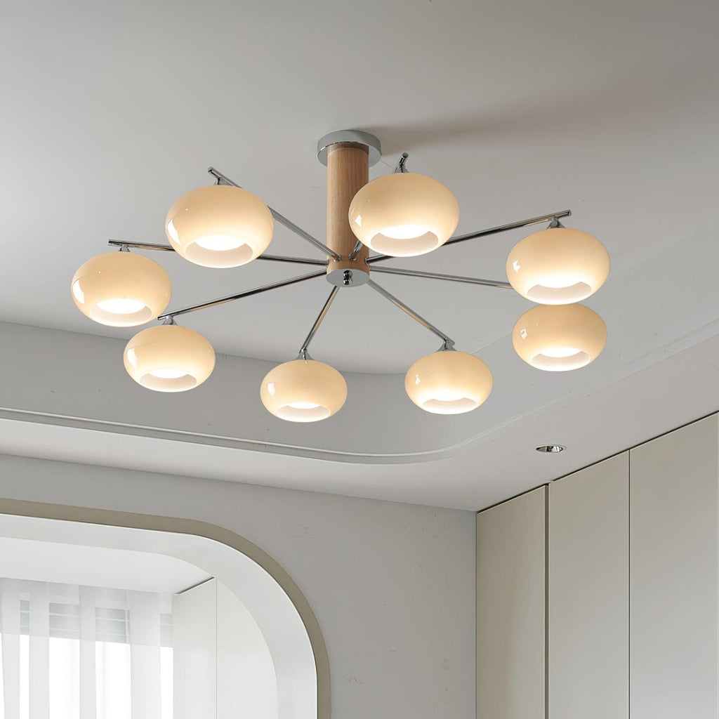 Looking up at a Clérachic chandelier with eight creamy glass shades spread on chrome arms below a layered white ceiling.