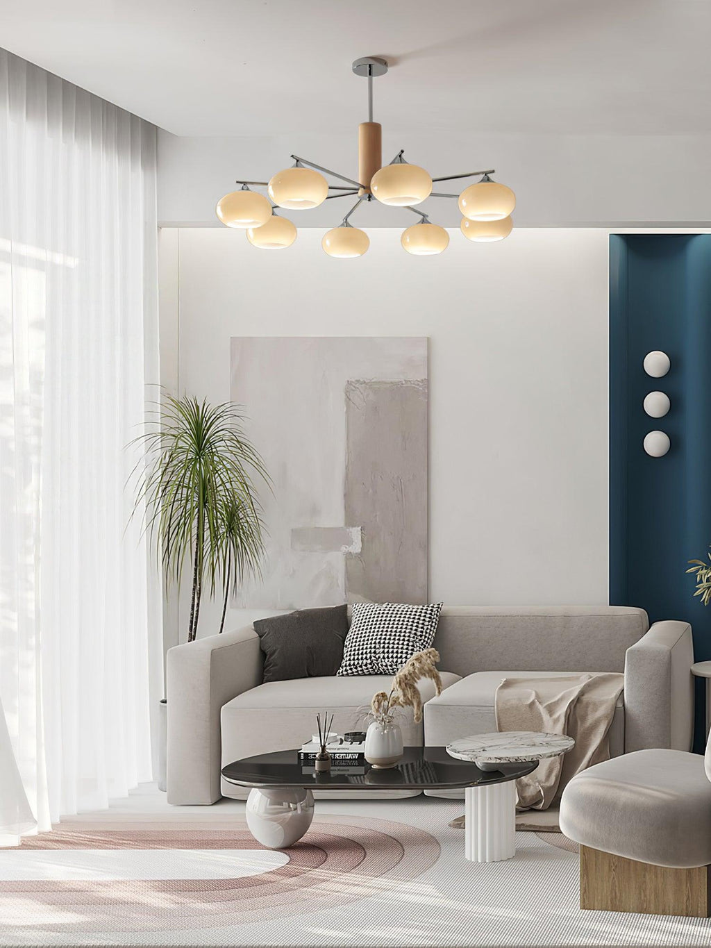 Wide view of a lit Clérachic chandelier above a living room with sheer curtains, a grey sofa, a black coffee table and a teal wall panel.