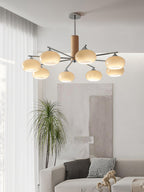 Portrait view of a lit Clérachic chandelier hung high in a living room, with a grey sofa and a patterned cushion below.