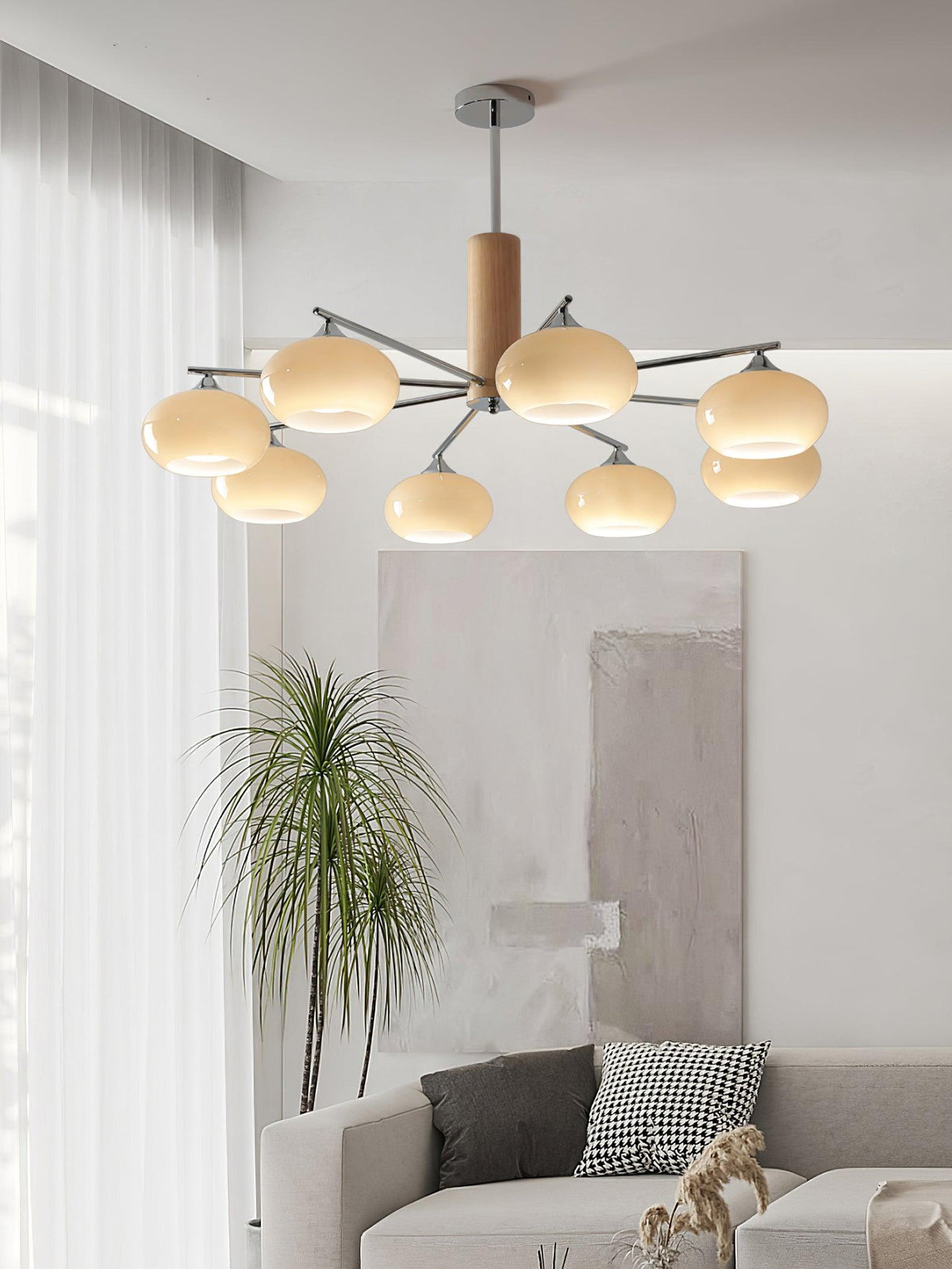 Portrait view of a lit Clérachic chandelier hung high in a living room, with a grey sofa and a patterned cushion below.
