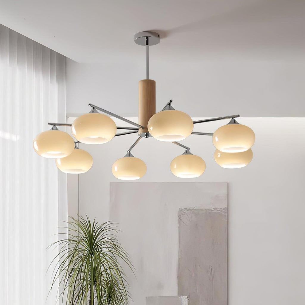 Clérachic chandelier with creamy glass shades hung above a living room corner, with a tall grass plant and a soft abstract wall panel.