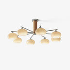 Eight-light chandelier from Clérachic with creamy glass shades and a wooden column, shown against a very pale grey backdrop.