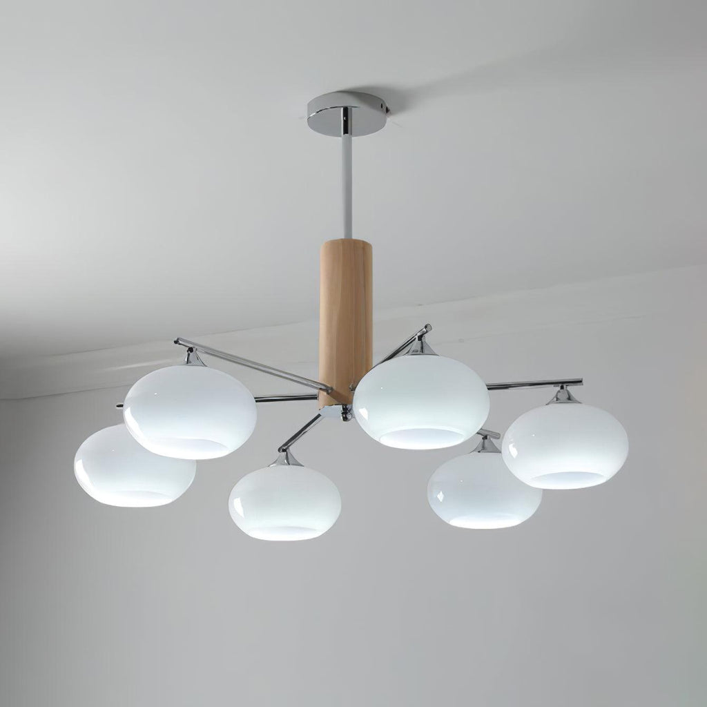 Lit chandelier from Clérachic with milk white glass shades giving a cool white glow, hung from a chrome rod below a plain ceiling.
