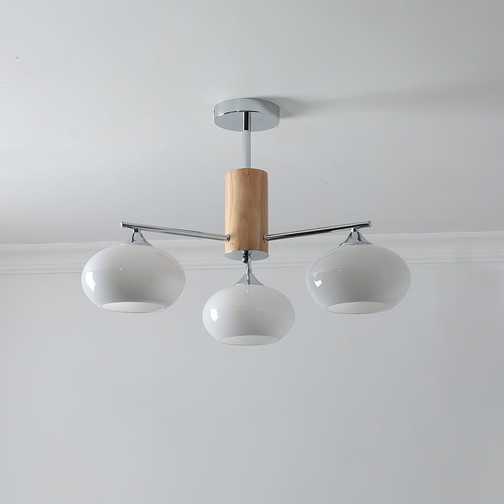 Three-light chandelier from Clérachic with milk white glass shades on chrome arms and a wooden column, below a white ceiling.