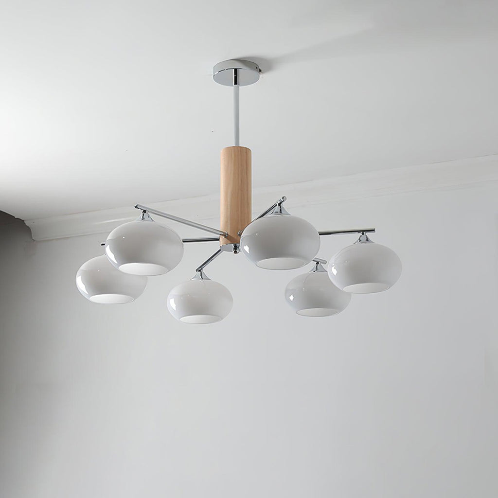 Unlit chandelier from Clérachic with milk white rounded glass shades, a wooden column and a chrome canopy on a pale grey wall.