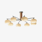 Eight creamy yellow glass shades glow on this Clérachic chandelier, seen on a pale background with its wooden column and chrome arms.
