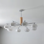 Chandelier from Clérachic with eight milk white glass shades spreading wide on chrome arms below a grey ceiling edge.