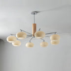 Lit Clérachic chandelier with eight creamy glass shades on chrome arms, hung from a rod below a grey ceiling with a white cornice.