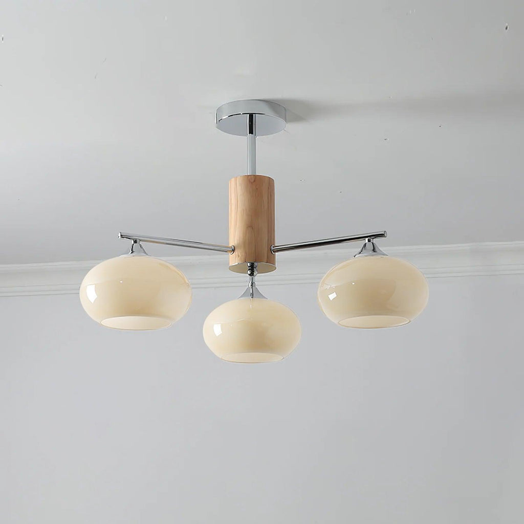 Three-light chandelier from Clérachic with wide creamy yellow glass shades on chrome arms, hung below a grey ceiling.