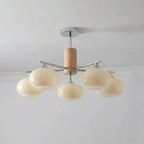 Five-light chandelier from Clérachic with creamy yellow glass shades, a wooden column and a chrome canopy, seen from below.
