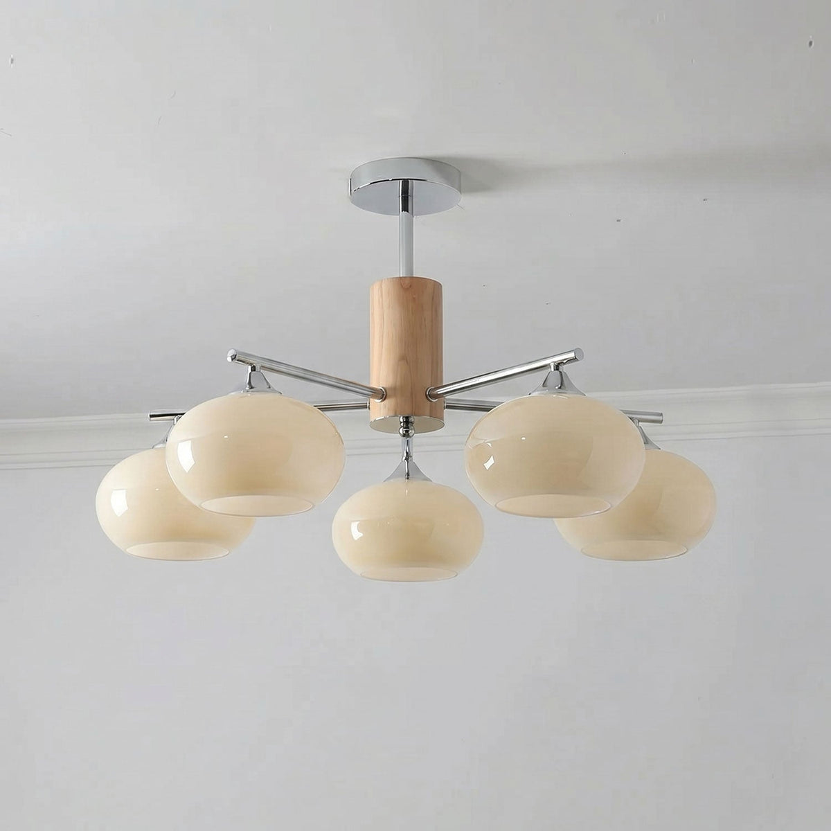Five-light chandelier from Clérachic with creamy yellow glass shades, a wooden column and a chrome canopy, seen from below.