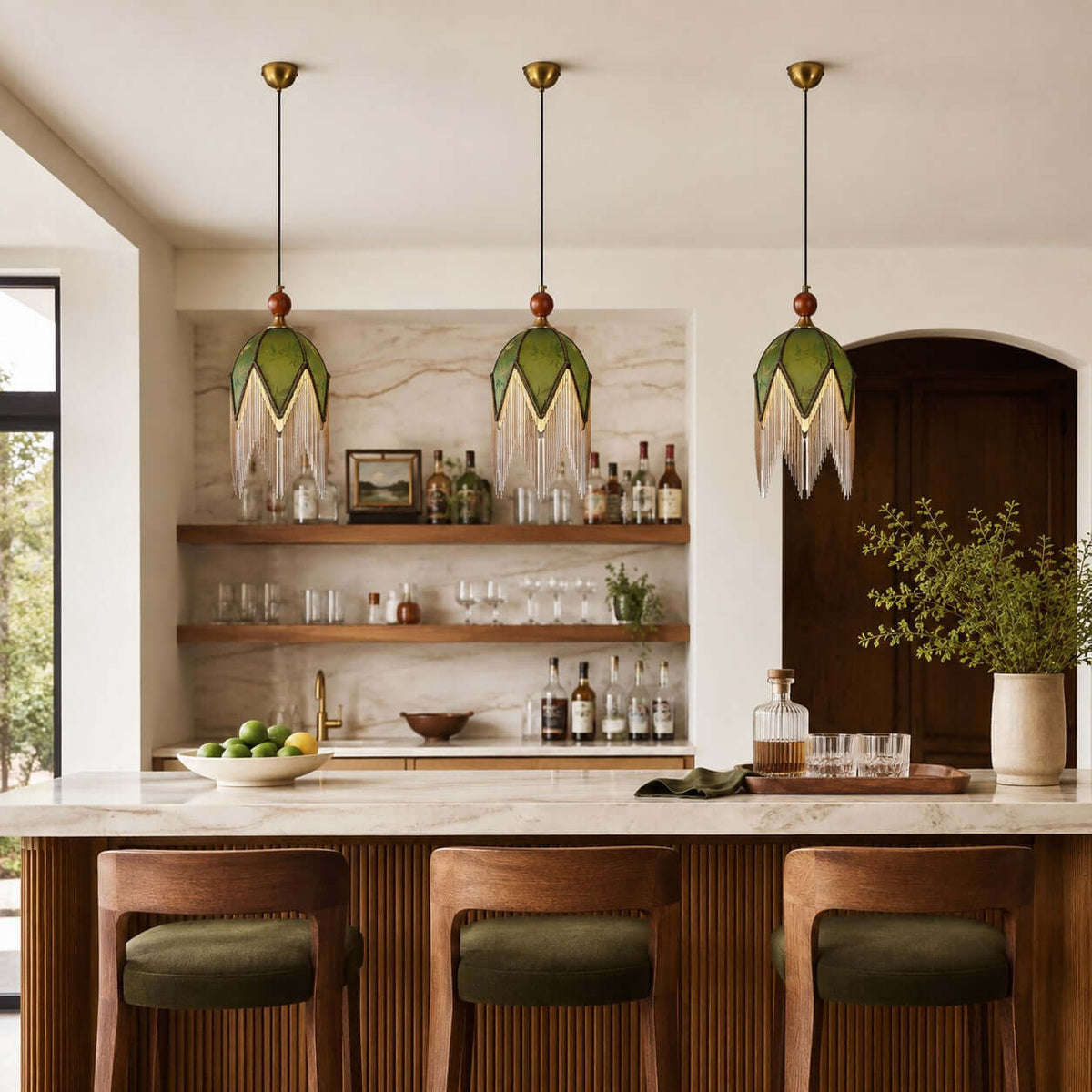 A row of three Clérachic pendants with olive shades hangs above a marble island, in front of open shelves of glasses and bottles.