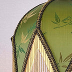 Close view of the green leaf-patterned fabric, black braided trim and fine bead fringe on this Clérachic pendant.