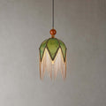 The petal-pointed olive shade of this Clérachic pendant, with a wooden bead at the top and a long fringe, on a grey backdrop.