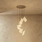 Clérachic empress gold chandelier lit warmly, its curved acrylic panes glowing beneath a round brass ceiling plate.