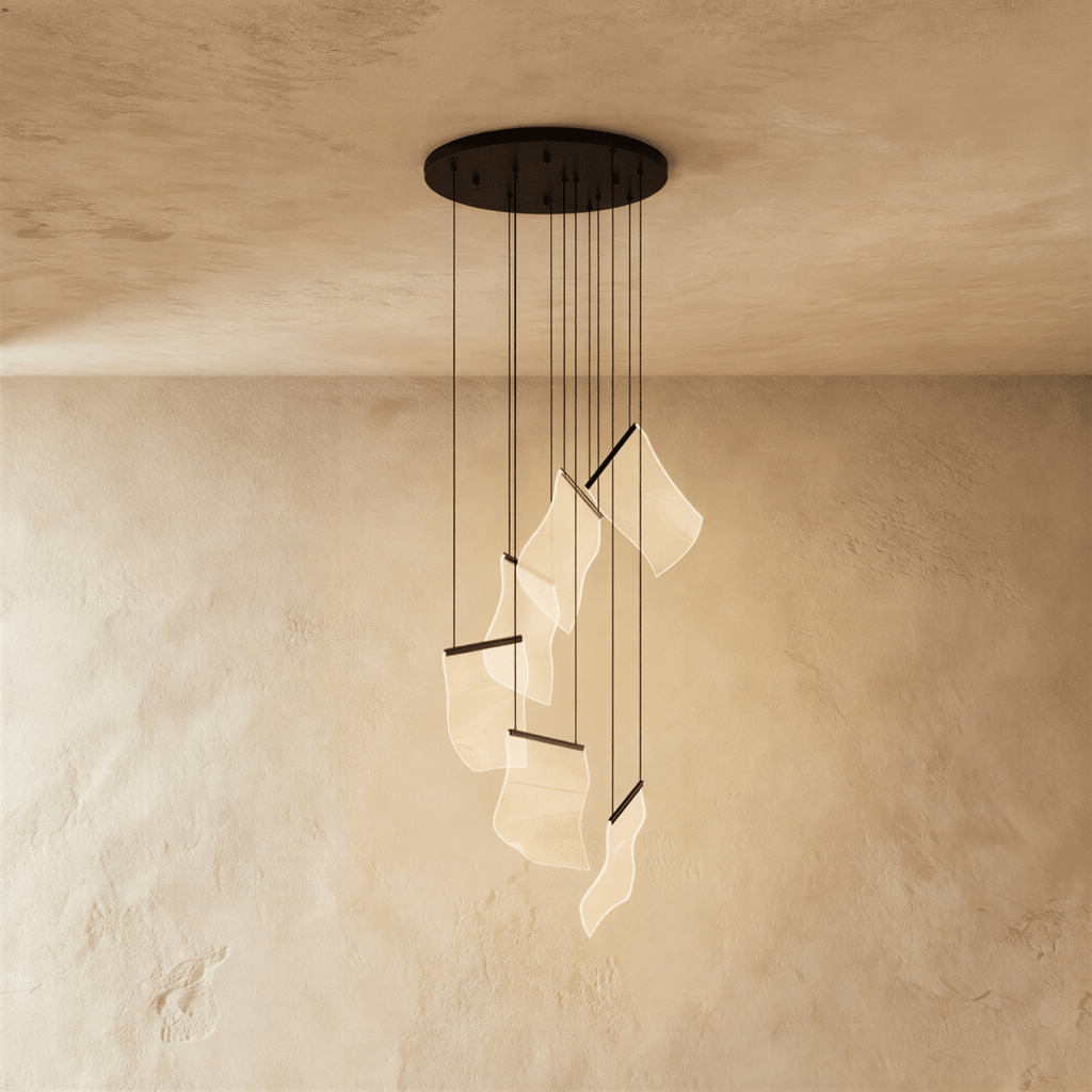 Clérachic brilliant black chandelier with a round ceiling plate, its wavy acrylic sheets glowing warm below.