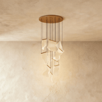 Clérachic gold chandelier shown against a plaster wall, its acrylic panes lit warm on slender hanging cords.