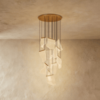 Clérachic gold chandelier with a fuller cluster of glowing acrylic sheets cascading from its brass ceiling disc.