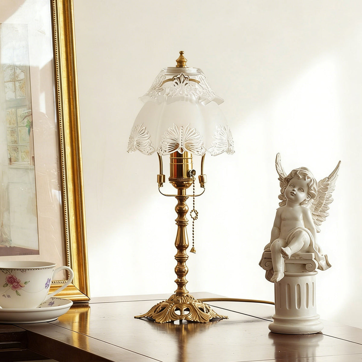 Unlit lamp with a pale scalloped glass shade, a brass stem with chain and a pierced base, beside a cherub figure, from Clérachic.