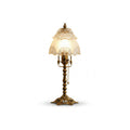 Brass table lamp with a lit frosted scalloped shade and a pull chain, with a soft shadow, on a white background, from Clérachic.