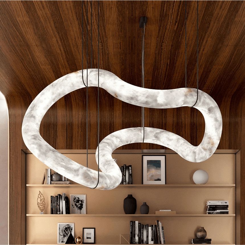 The Clérachic Ethereal chandelier under a walnut ceiling, its curved stone tube lit warm.