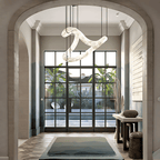 The Clérachic Ethereal chandelier in a tall arched hall, palms visible through steel windows.