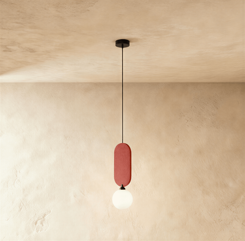 Clérachic single pendant with a brick red fabric pill panel above a milk white glass globe, hung against plaster.