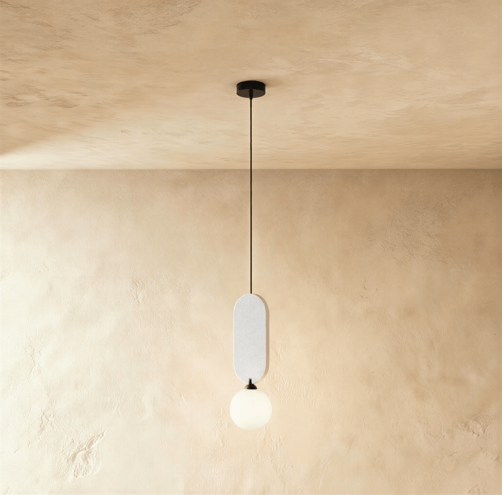 Clérachic single pendant with a pale white fabric pill panel over a milk white glass globe on a black cord.