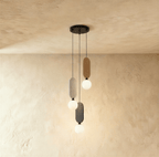 Clérachic three-head pendant on a round black canopy, with beige, light grey and charcoal fabric panels and white globes.