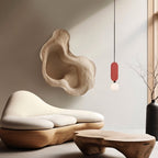 Clérachic red-panel pendant with a white glass globe, hung beside a sculpted cream sofa and a live-edge wood coffee table.