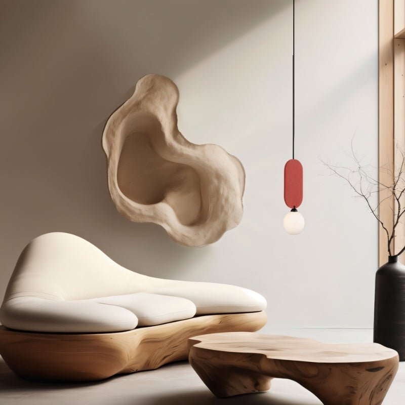 Clérachic red-panel pendant with a white glass globe, hung beside a sculpted cream sofa and a live-edge wood coffee table.